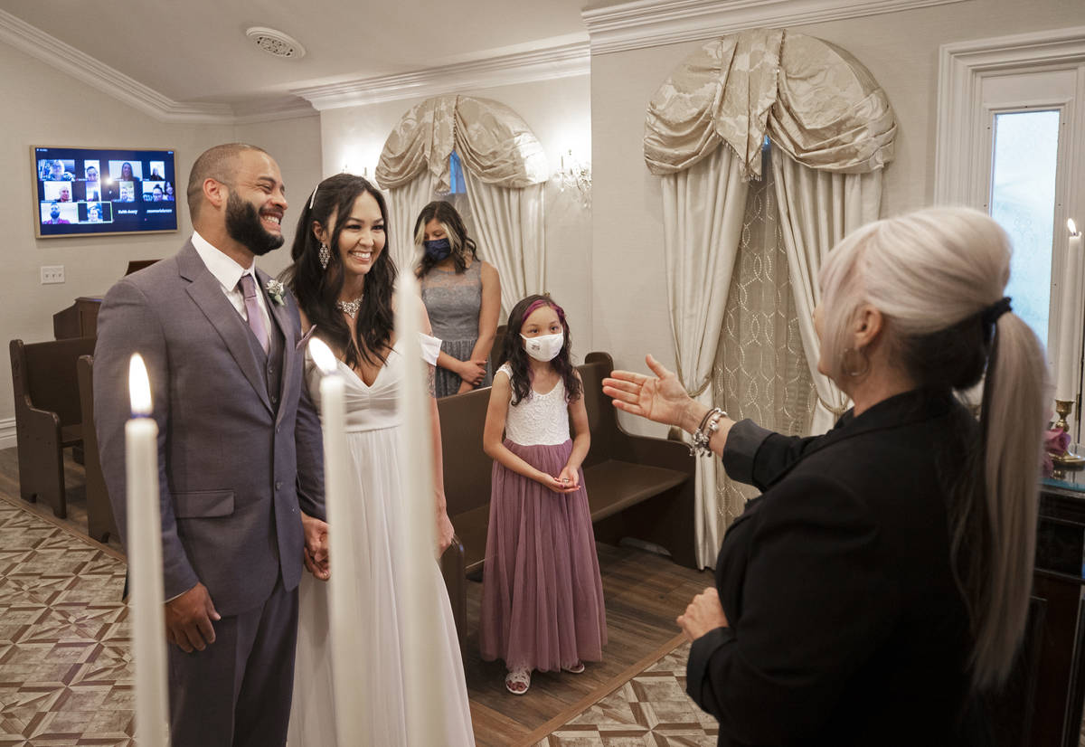 William and Brandi Alexander, from Anchorage, Alaska, listen to their officiant Ginnie Wilson d ...