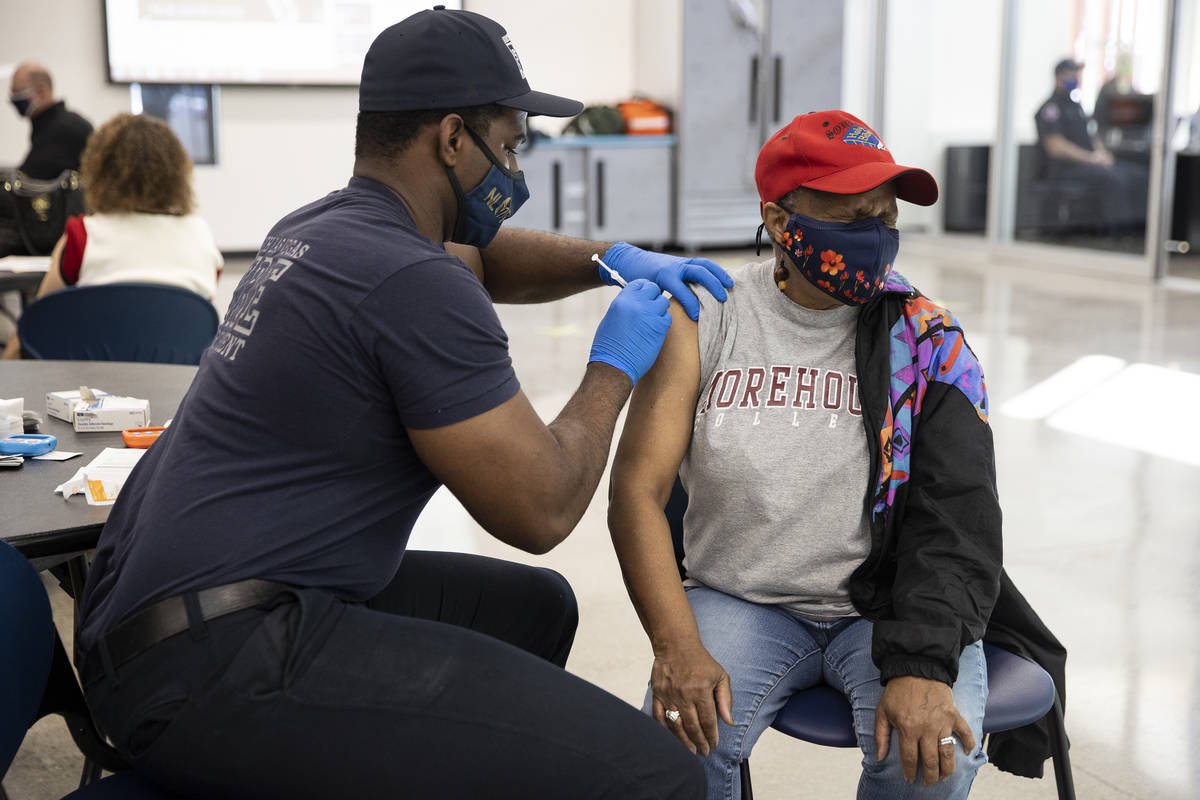 North Las Vegas Fire Department Firefighter Dominic True administers the COVID-19 vaccine to He ...