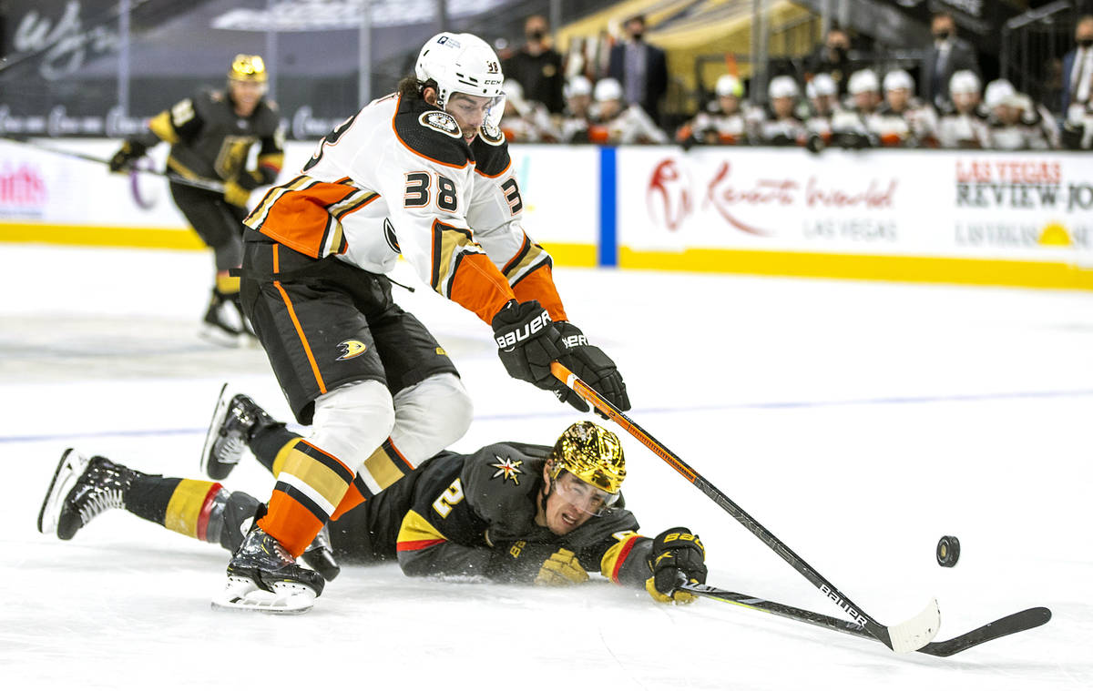 Golden Knights defenseman Zach Whitecloud (2) is taken down to the ice by Anaheim Ducks center ...