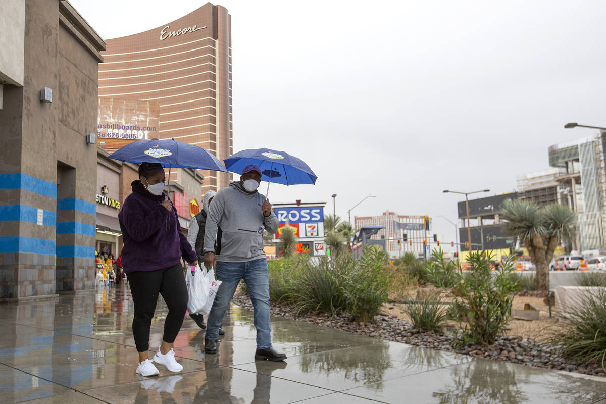 Mary Areh and Tony Areh, of Atlanta, walk north on the Las Vegas Strip while it rains on Friday ...