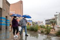 Mary Areh and Tony Areh, of Atlanta, walk north on the Las Vegas Strip while it rains on Friday ...