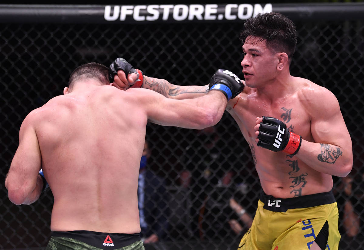 (R-L) Maki Pitolo punches Julian Marquez in their middleweight fight during the UFC 258 event a ...