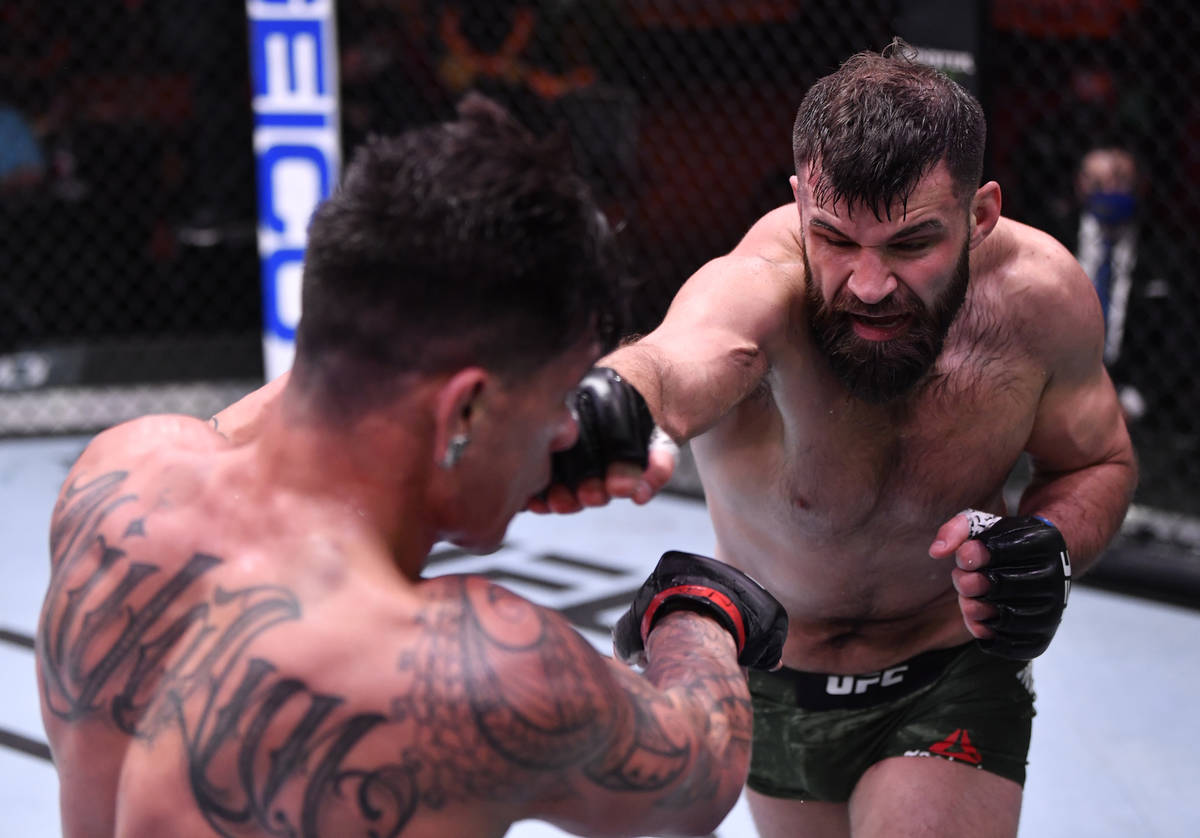 (R-L) Julian Marquez punches Maki Pitolo in their middleweight fight during the UFC 258 event a ...