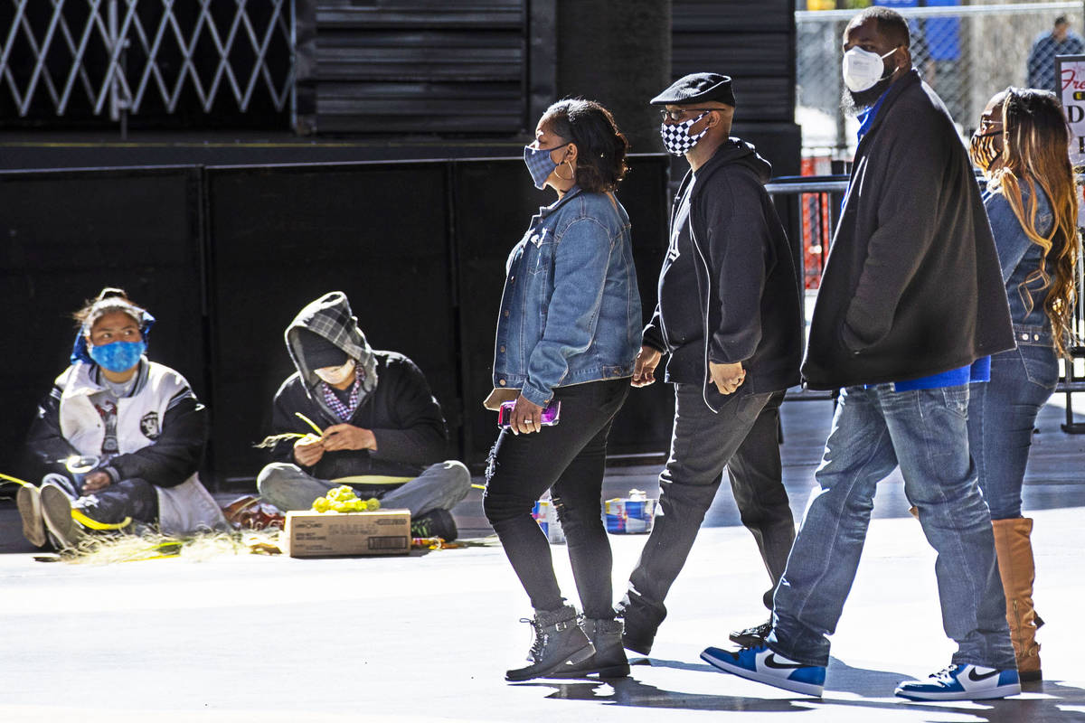 People wearing face masks, including cloth and KN95 style ones, walk along the Fremont Street E ...