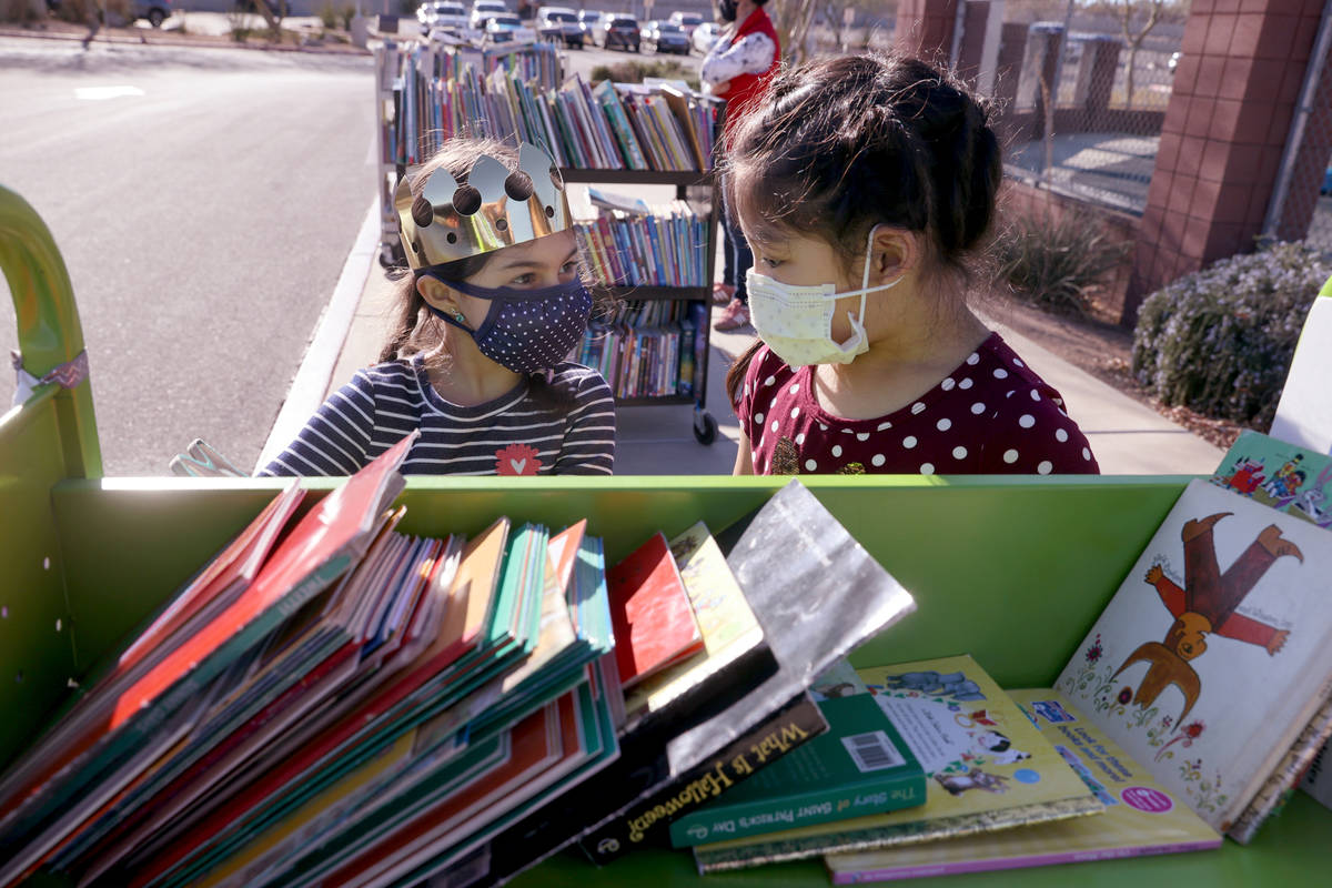 Amaliya Yusupova, 7, and Maiyah Concepcion, 8, choose books during a school supply distribution ...