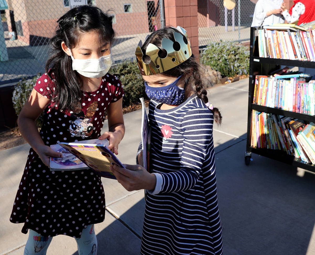 Maiyah Concepcion, 8, left, and Amaliya Yusupova, 7, choose books during a school supply distri ...