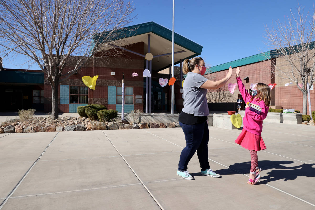 Kindergarten teacher Molly Wood gives an "air high-five" to first grader Caiome Macka ...