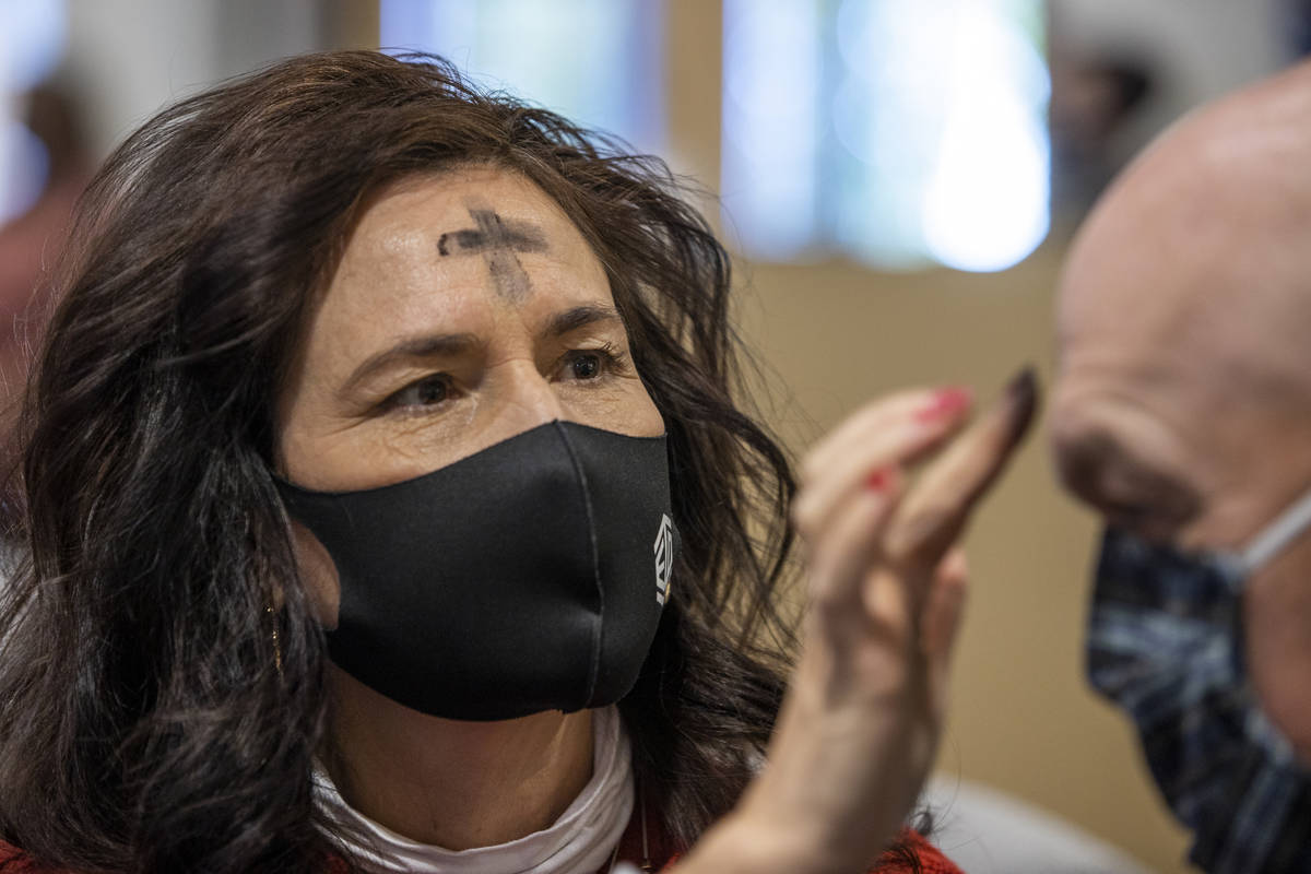 Shelley Flandermeyer places ashes in the sign of a cross on husband Matt's forehead during an A ...