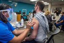 Noel Madic, RN, left, with the University Medical Center injects UMC resident physician Austin ...