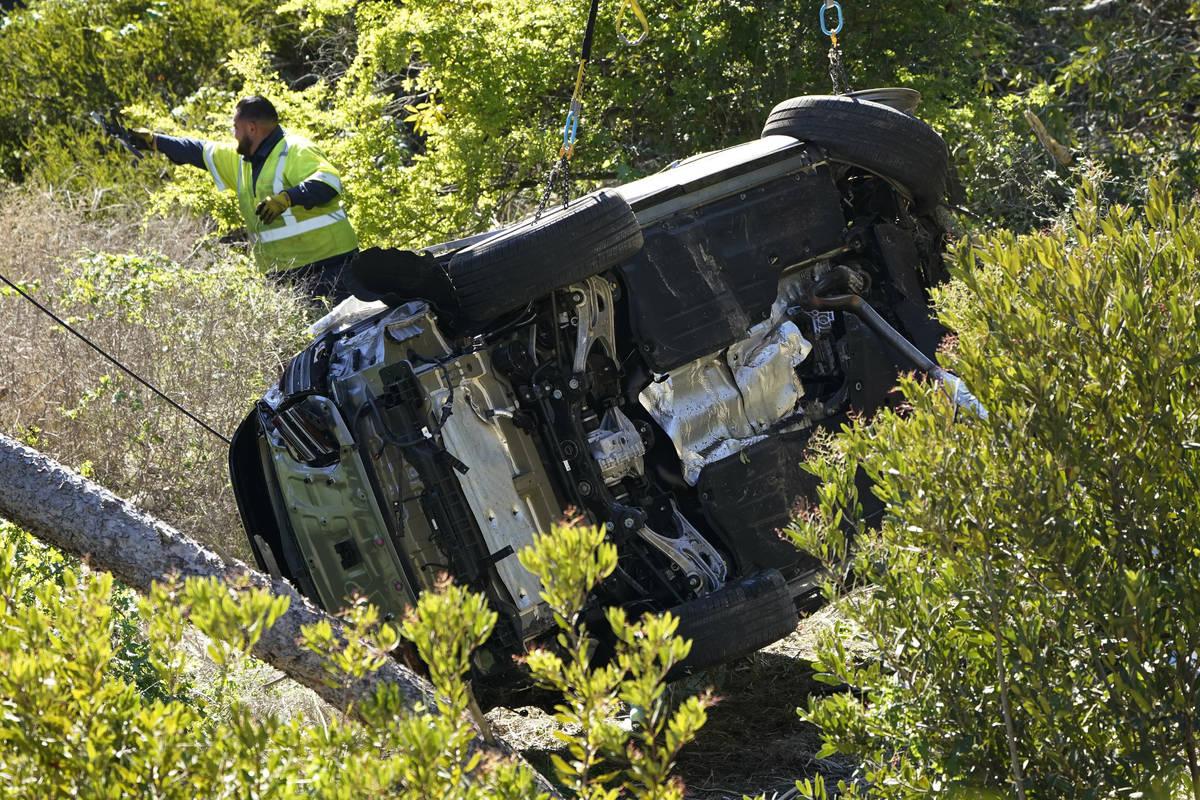 Workers move a vehicle on its side after a rollover accident involving golfer Tiger Woods Tuesd ...