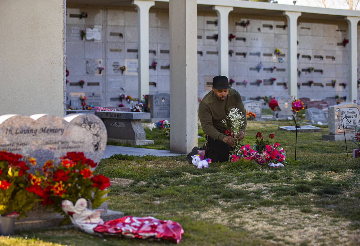Brian Bradford arranges roses by the grave of his daughter, Briana Bradford. She died at age 7 ...