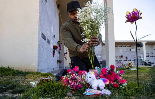 Brian Bradford arranges roses and flowers by the grave of his daughter, Briana Bradford, on the ...