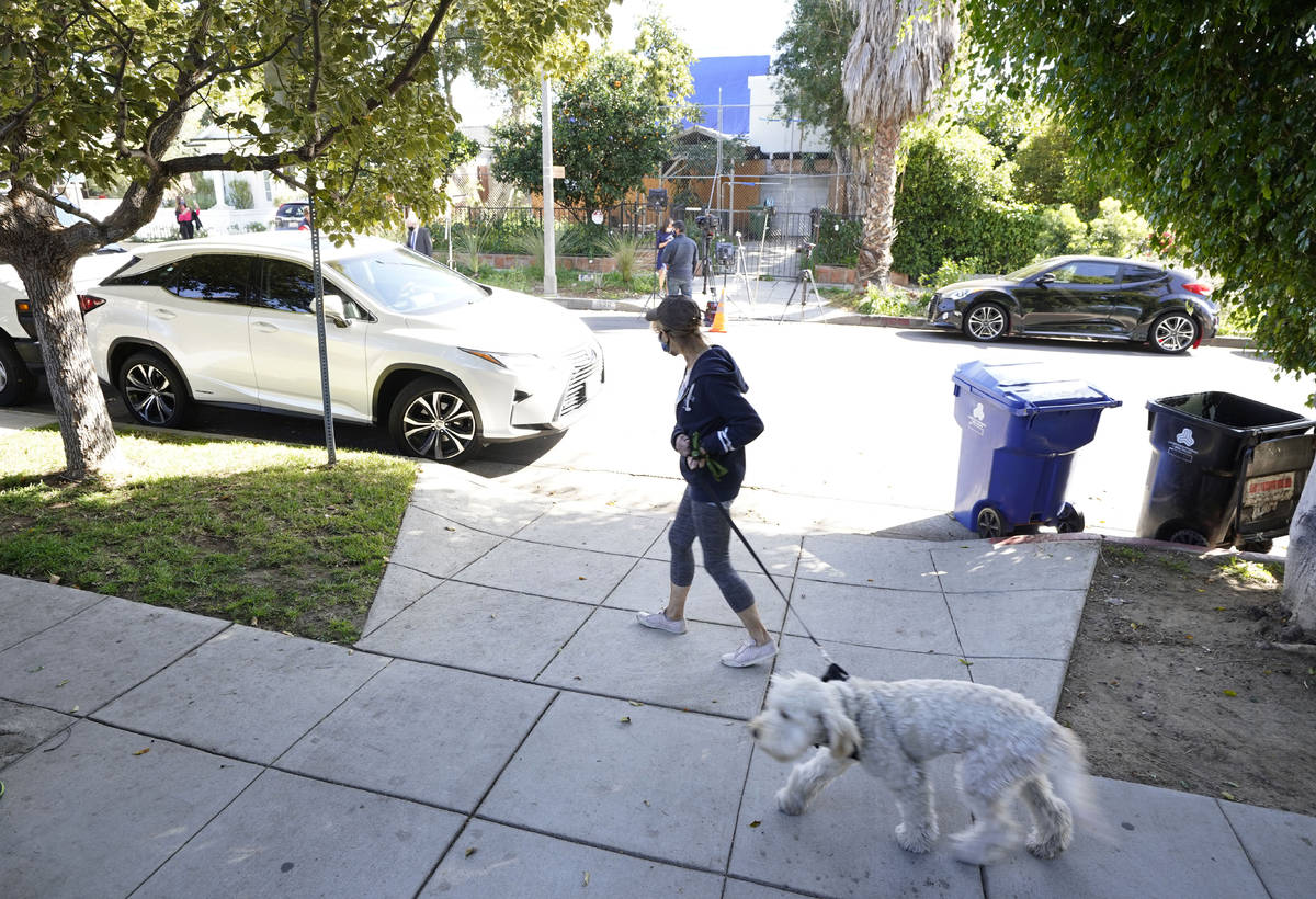 A woman walks her dog across the street from an area on North Sierra Bonita Ave. where Lady Gag ...