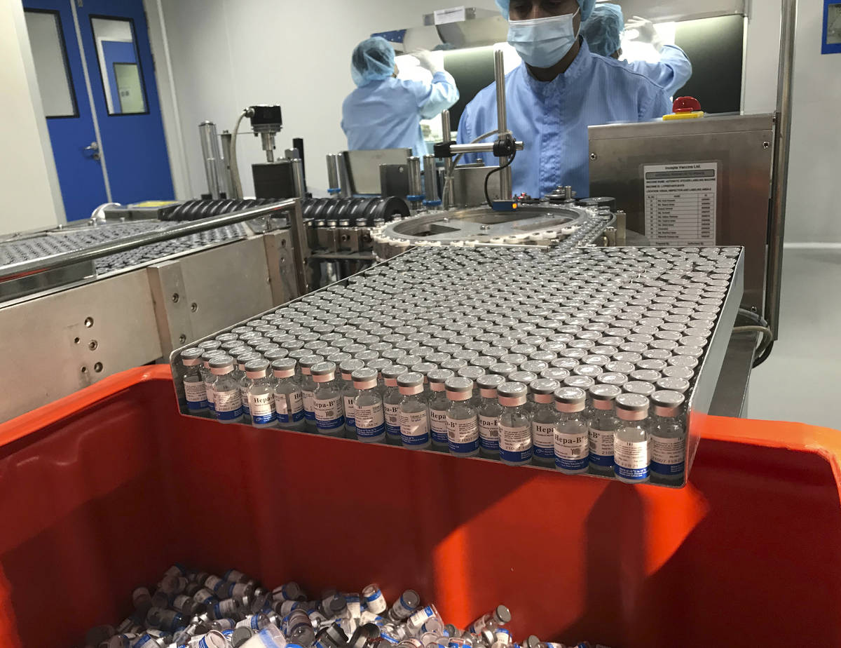 Production personnel perform the labeling operation of inspected vaccine vials inside the Incep ...