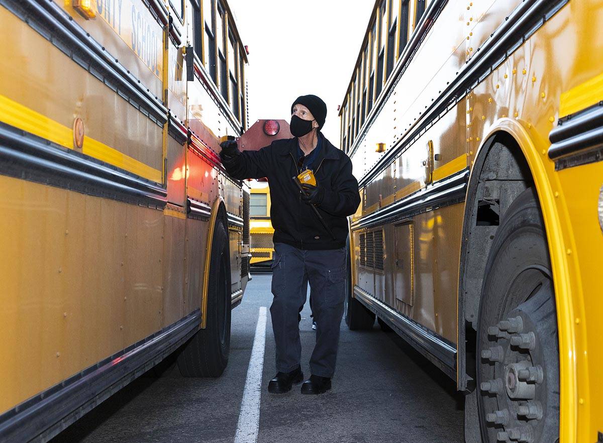Donald Brace, a school bus driver, inspects his bus as he prepares to head out to pick up stude ...