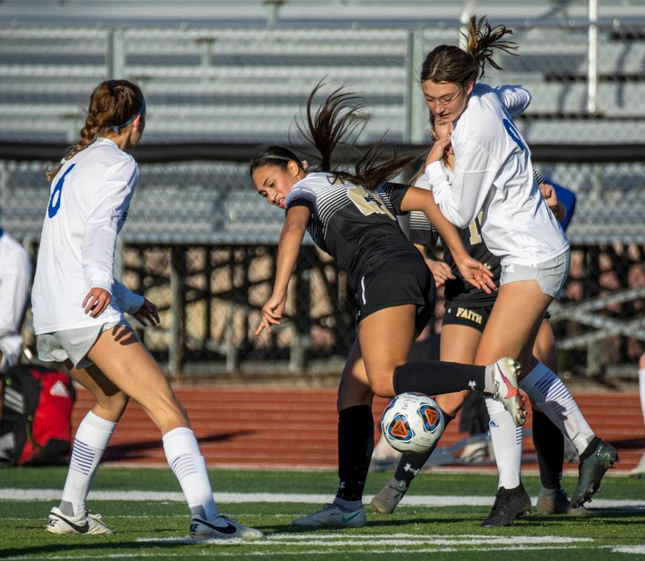 Faith Lutheran's Aurrianna Parker (21, center) fights for the ball with Bishop Gorman's Rachel ...