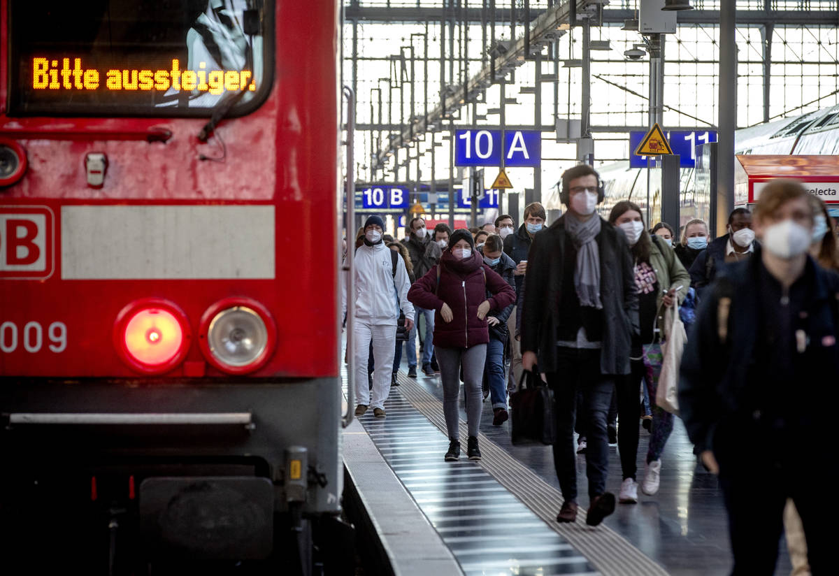 Commuters wearing face masks walk on a platform in the main train station in Frankfurt, Germany ...