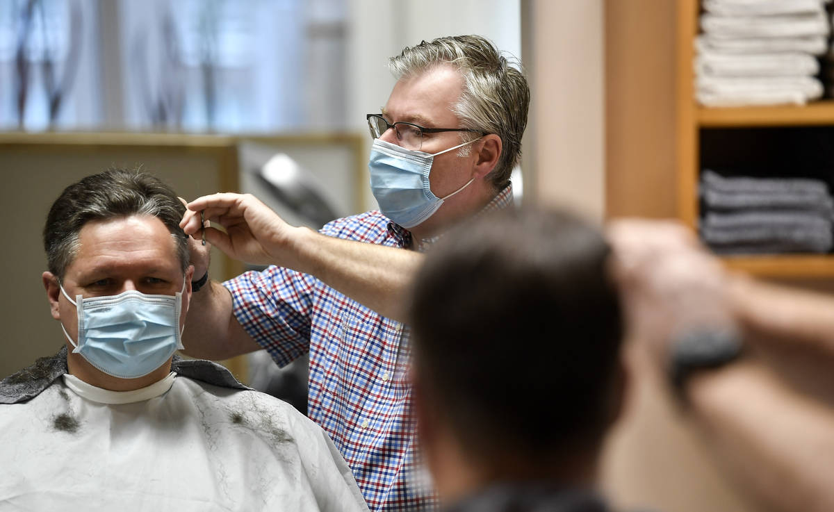 Hairdresser Holger Augustin cuts hair of a customer at his barber shop in Gelsenkirchen, German ...