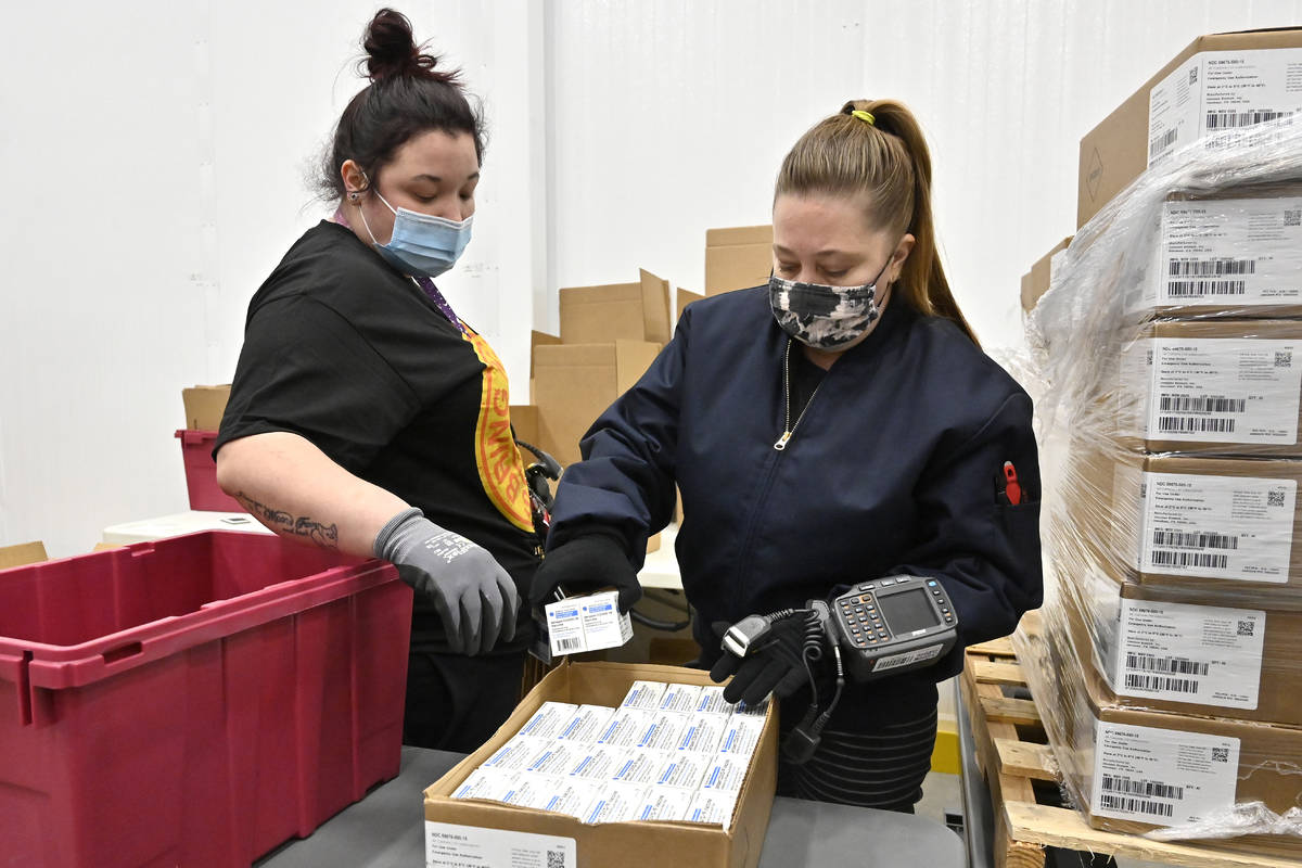 Employees with the McKesson Corporation scan a box of the Johnson & Johnson COVID-19 vacci ...