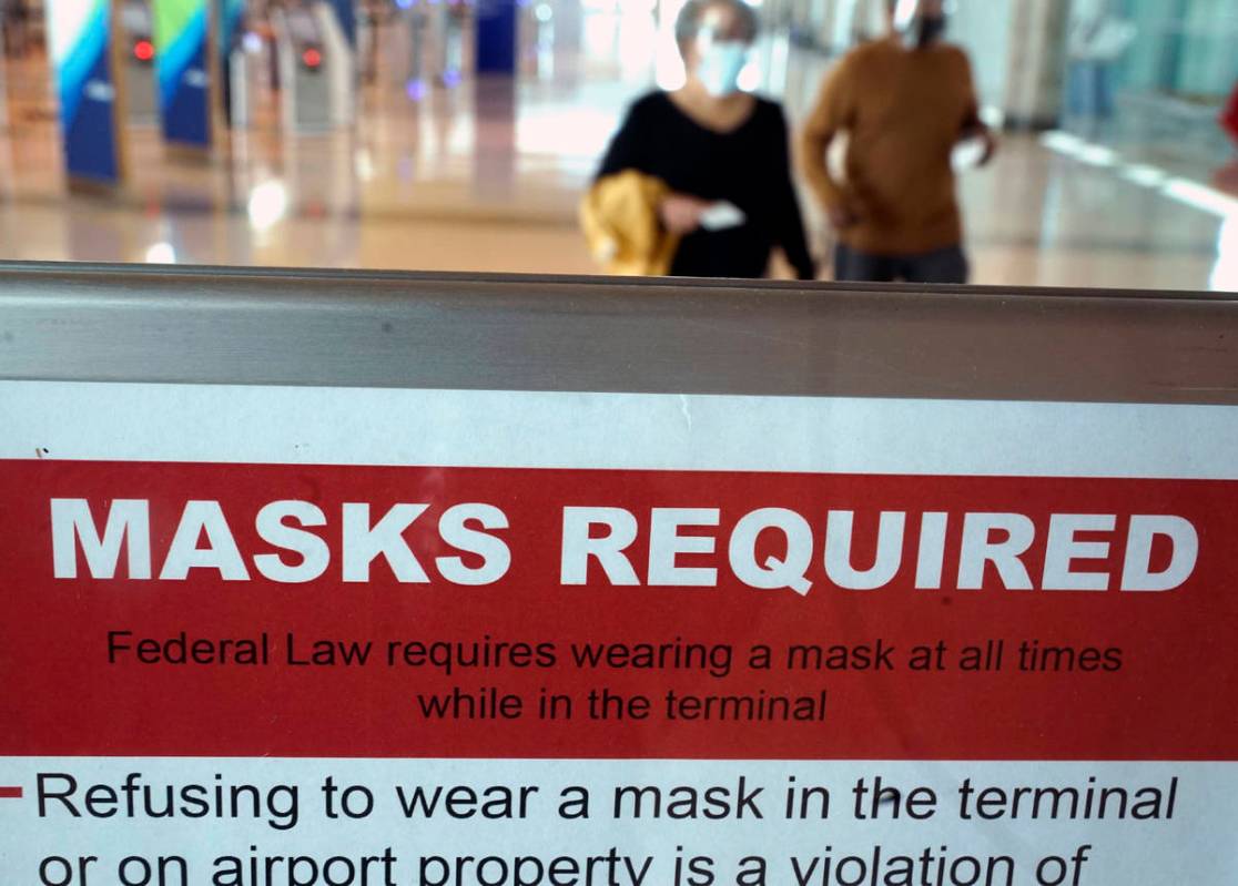To prevent the spread of Covid-19, a sign directs travelers to wear masks at Love Field Tuesday ...