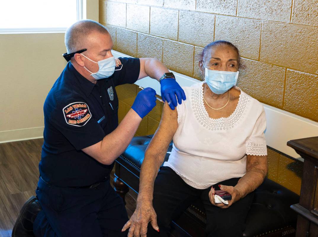 Chris Racine of Las Vegas Fire Rescue administers a COVID-19 vaccine to Rosa Nunez, 92, a resid ...