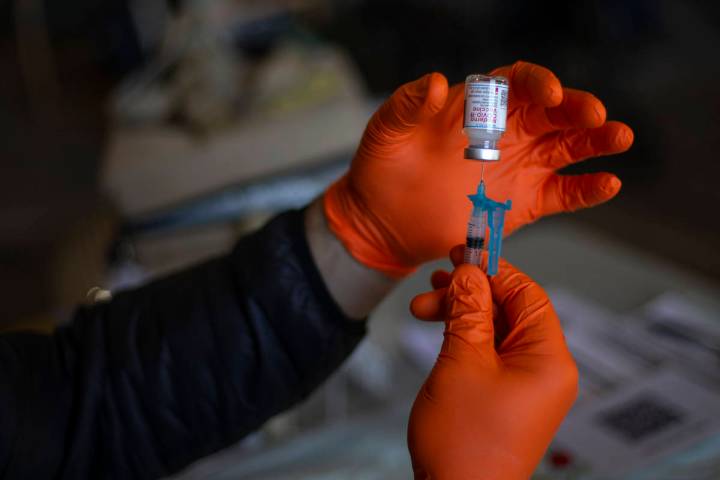 Paramedic Craig Johnson draws a dose of the Moderna COVID-19 vaccine in preparation for Guardia ...