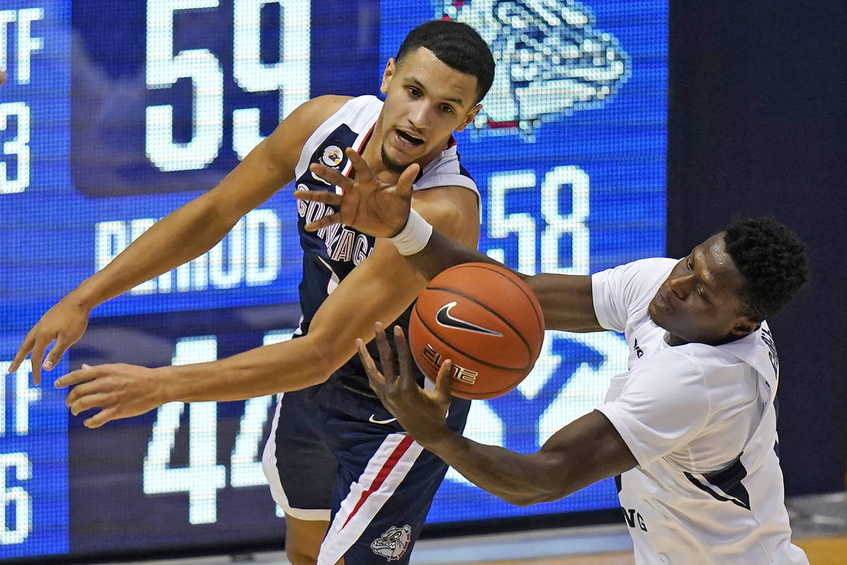 Gonzaga guard Jalen Suggs, rear, and BYU forward Gideon George, right, battle for a rebound in ...