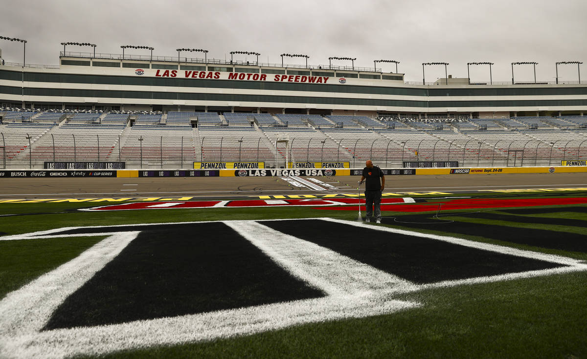 Dale Pantelakis, of Ananta Surfaces, paints logos on the infield grass ahead of the Pennzoil 40 ...