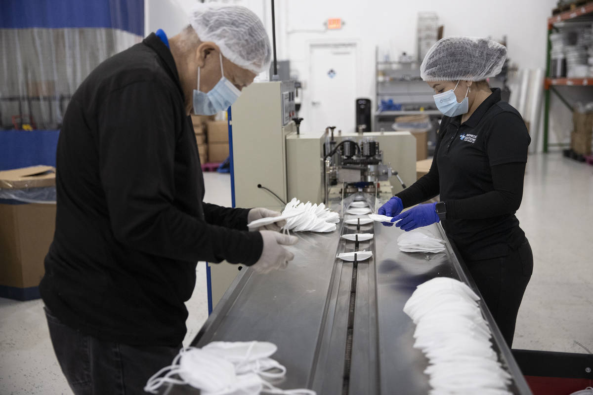 Manufacturing technicians Homar Luna, left, and Angelica Aguas check the quality of N95 masks a ...