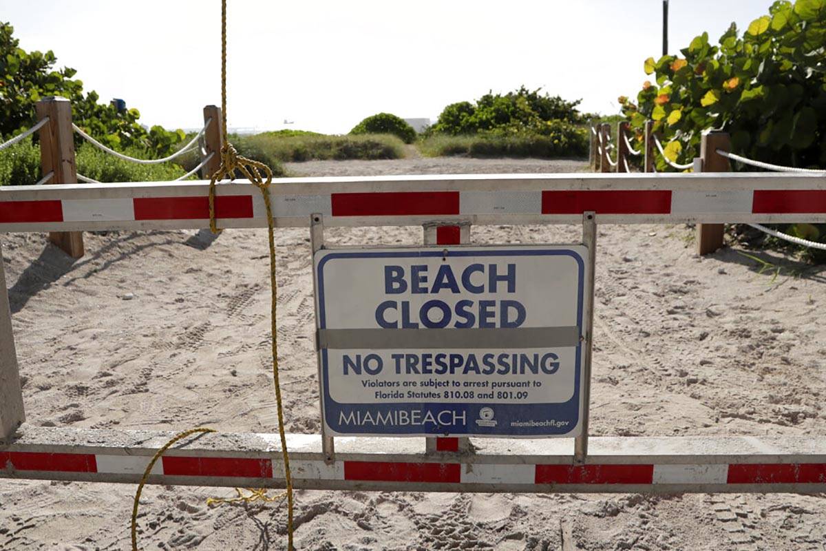 A sign is posted at a closed entrance to the beach during the new coronavirus pandemic, Friday, ...