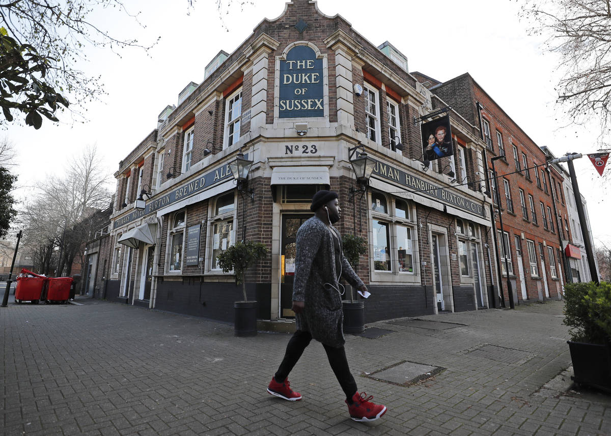 A man walks past the Duke of Sussex pub with a sign depicting the image of Britain's Prince Har ...
