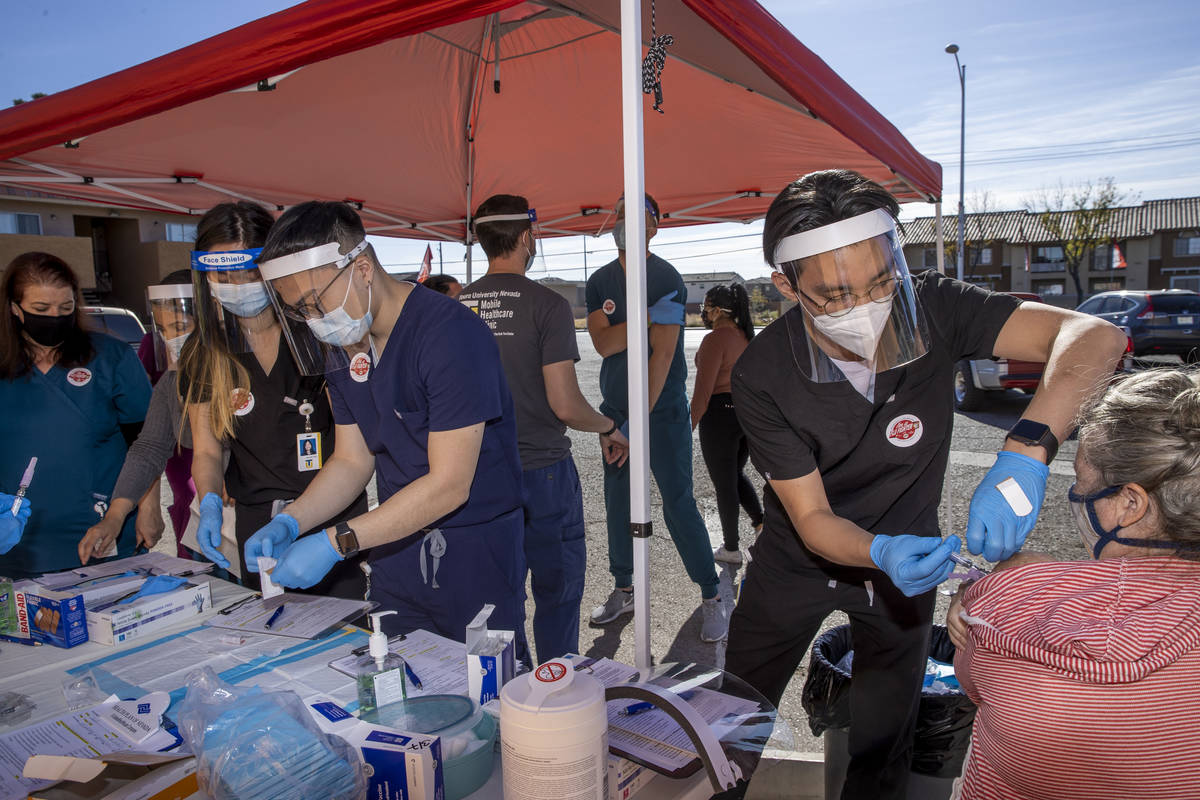 Touro University physician assistant student Andrew Trinh, right, gives another flu vaccine sho ...