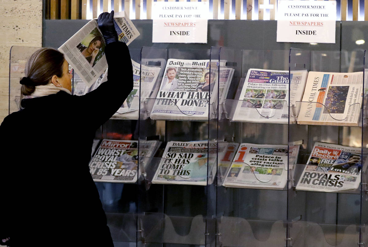 A customer takes a copy of a newspaper headlining Prince Harry and Meghan’s explosive TV ...