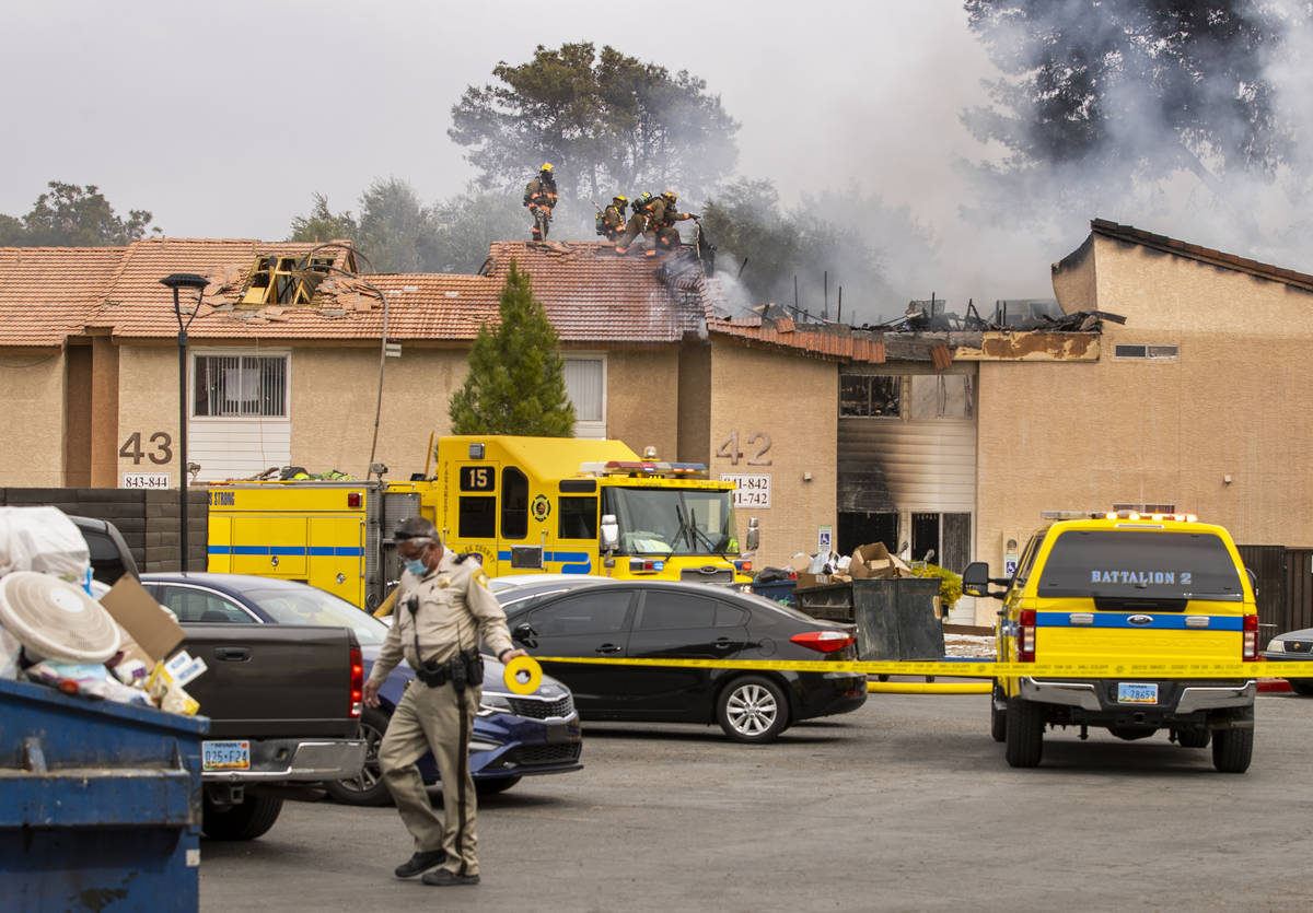 Police tape goes up as Clark County and Las Vegas Fire Department firefighters work from the ro ...