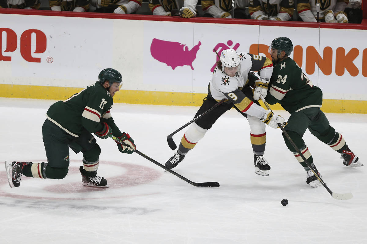 Vegas Golden Knights' Cody Glass (9) tries to gain control of the puck against Minnesota Wild's ...