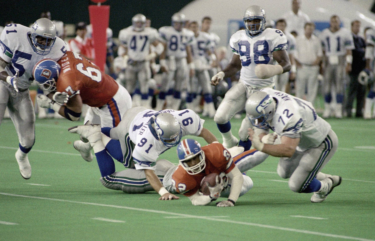 Denver Broncos wide receiver Vance Johnson (82) is tackled by Seattle Seahawks Darrin Miller (9 ...