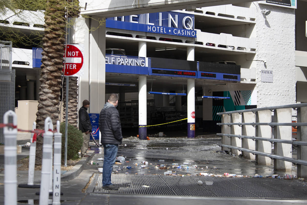 Bystanders watch flooding in the LINQ parking garage rush into a wash on Friday, March 12, 2021 ...