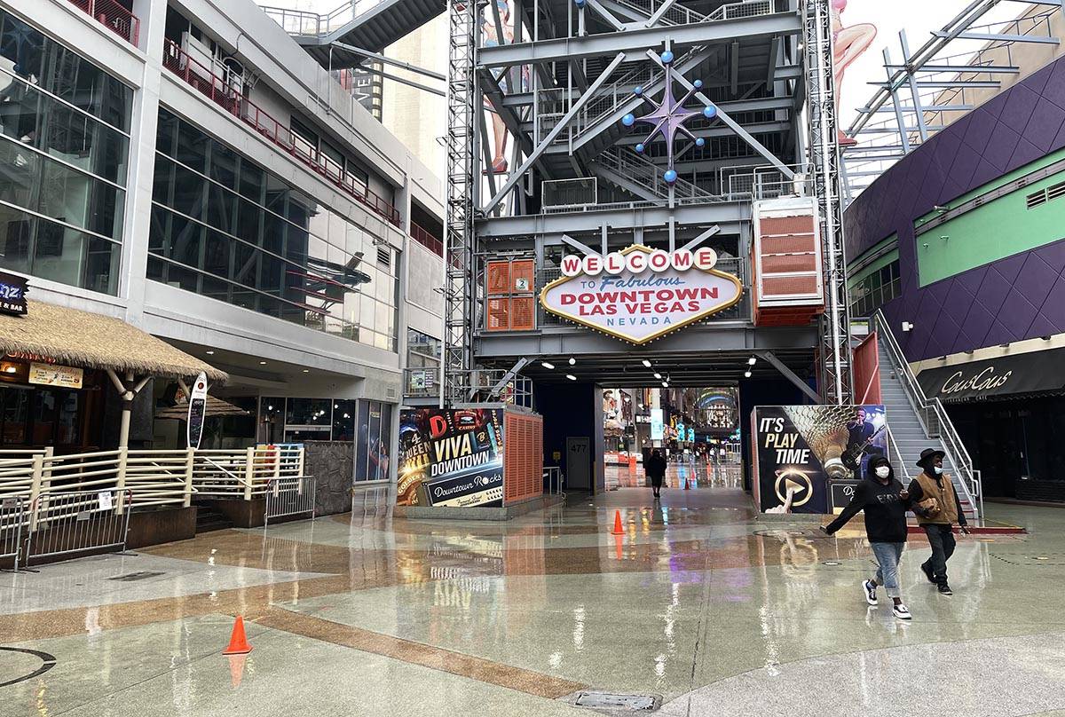 A few pedestrians walk in light rain at the Fremont Street Experience early Friday, March 12, 2 ...