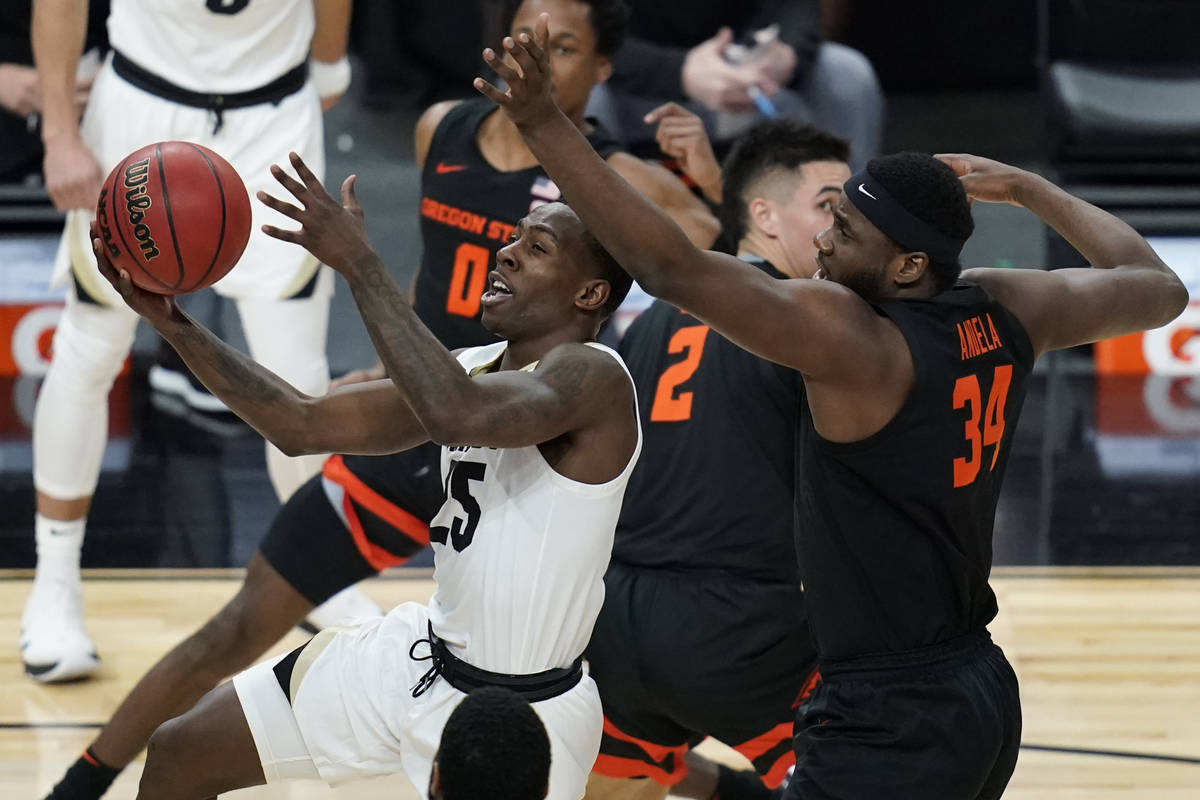 Colorado's McKinley Wright IV (25) shoots around Oregon State's Rodrigue Andela (34) during the ...