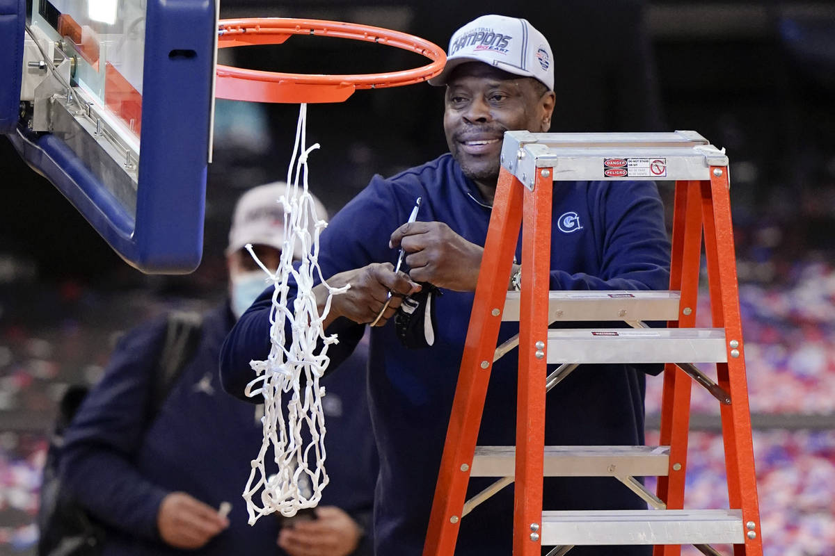 Georgetown head coach Patrick Ewing cuts down the net after an NCAA college basketball game aga ...