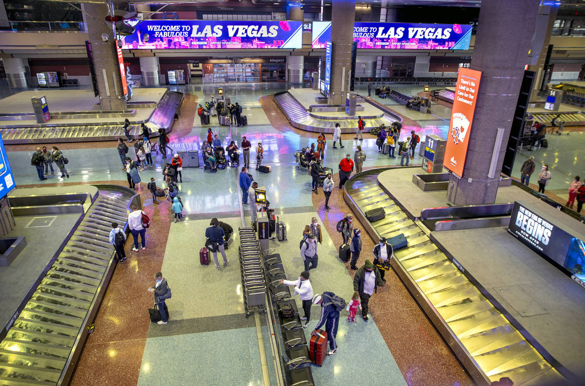 People retrieve their baggage at Terminal 1 as holiday travel at McCarran International Airport ...