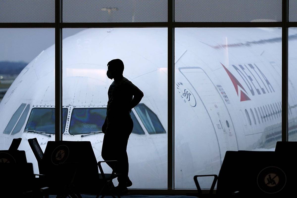 A passenger wears a face mask to help prevent the spread of the new coronavirus as he waits for ...