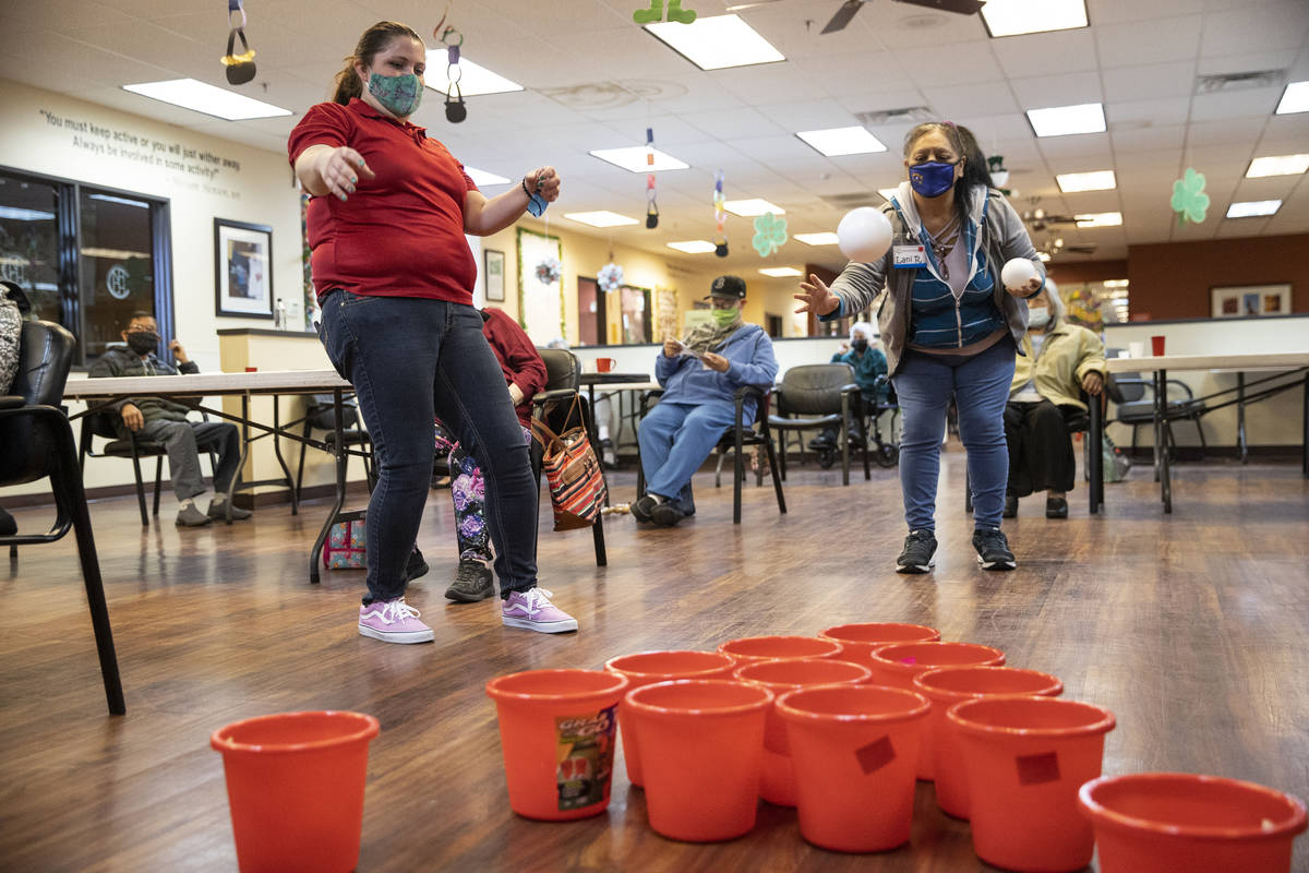 Lead program assistant Samantha Molloy, left, watches as Lani Reardon, 61, throws a ball during ...