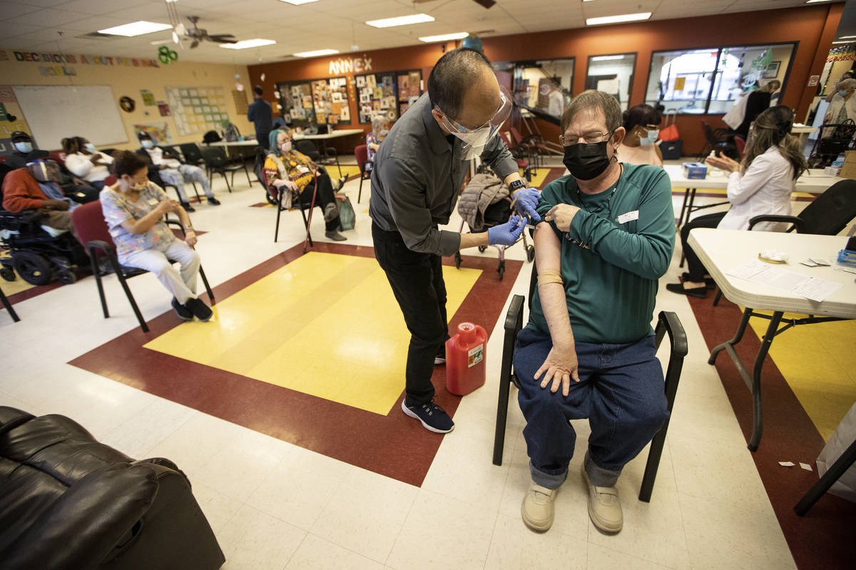 Alex Vong, left, pharmacy manager at Albertsons, administers the second dose of the COVID-19 va ...