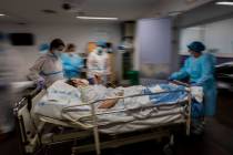 In this Feb. 17, 2021, file photo, a COVID-19 patient is transferred to the "red zone," an area ...