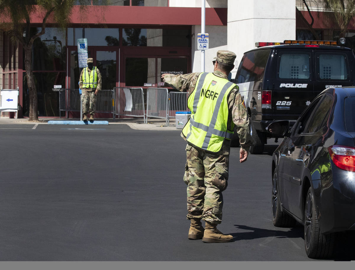 A member of the National Disaster Response Force directs traffic as a car arrives at a COVID-19 ...