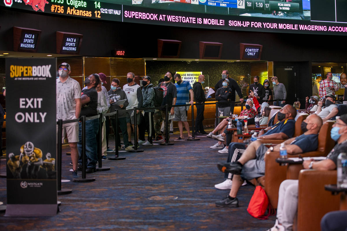 Bettors wait in line as others enjoy the games above during opening day of NCAA Tournament play ...