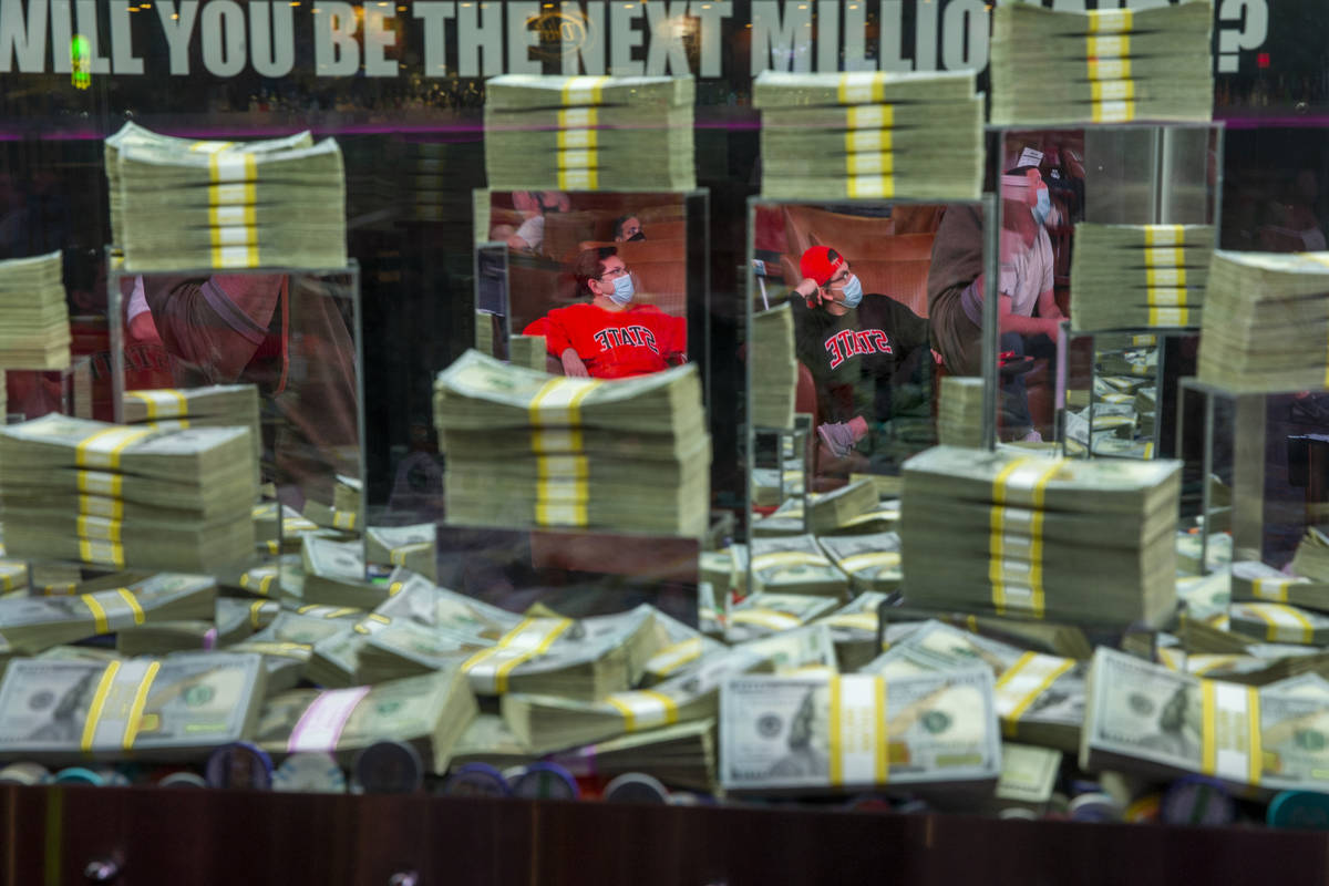 (From left) Aaron and Matt Tanner of Tulsa are reflected in the glass of a money case as they w ...