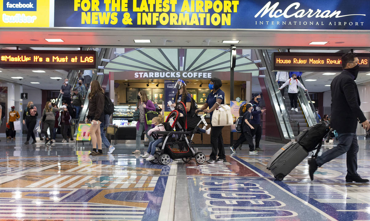 People move throughout baggage claim, wearing personal protective equipment to prevent the spre ...