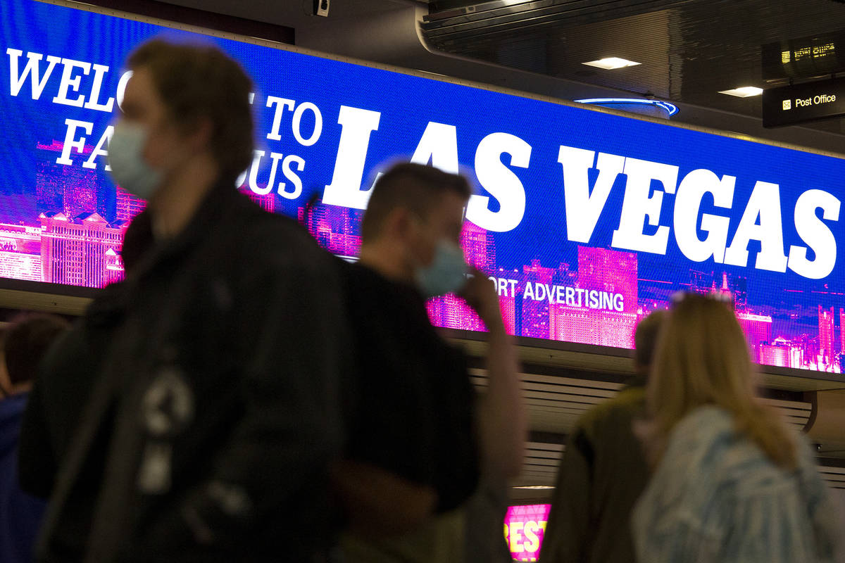 People move throughout baggage claim, wearing personal protective equipment to prevent the spre ...